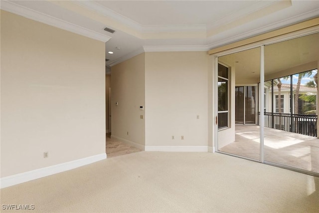 empty room with visible vents, baseboards, light colored carpet, ornamental molding, and a raised ceiling