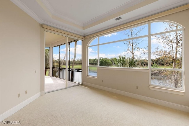 unfurnished room with carpet, baseboards, a tray ceiling, a water view, and crown molding