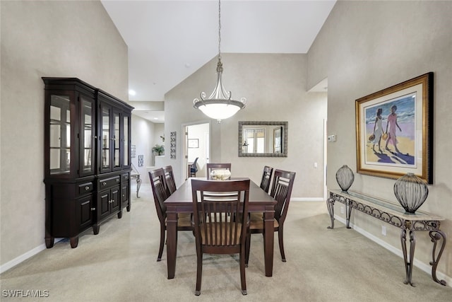 dining area featuring light colored carpet and high vaulted ceiling