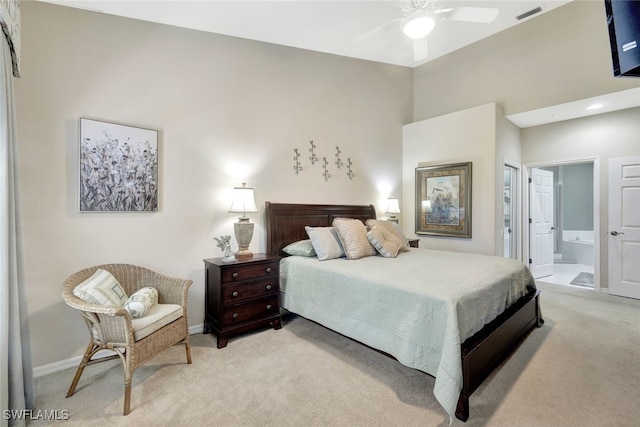 bedroom with connected bathroom, light colored carpet, and ceiling fan