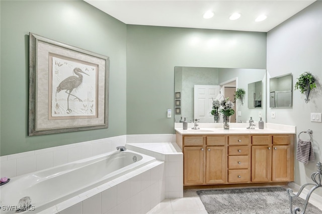 bathroom featuring tile patterned flooring, vanity, and a relaxing tiled tub