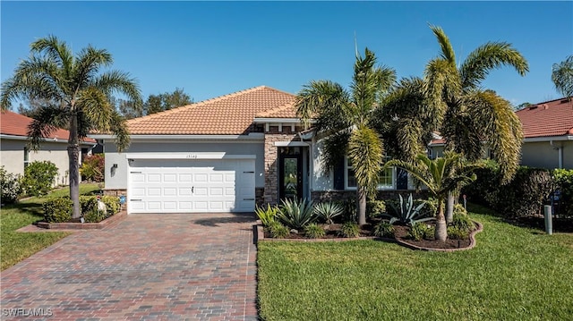 15140 Yellow Wood Dr, Alva, FL 33920 - view of front of house with an attached garage, stone siding, a tiled roof, a front yard, and decorative driveway
