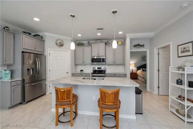 kitchen featuring gray cabinetry, a kitchen island with sink, hanging light fixtures, sink, and stainless steel appliances