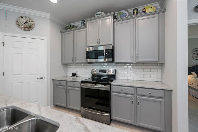 kitchen with decorative backsplash, crown molding, gray cabinetry, and appliances with stainless steel finishes