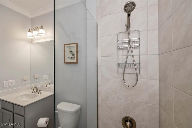 bathroom featuring vanity, toilet, crown molding, and a tile shower