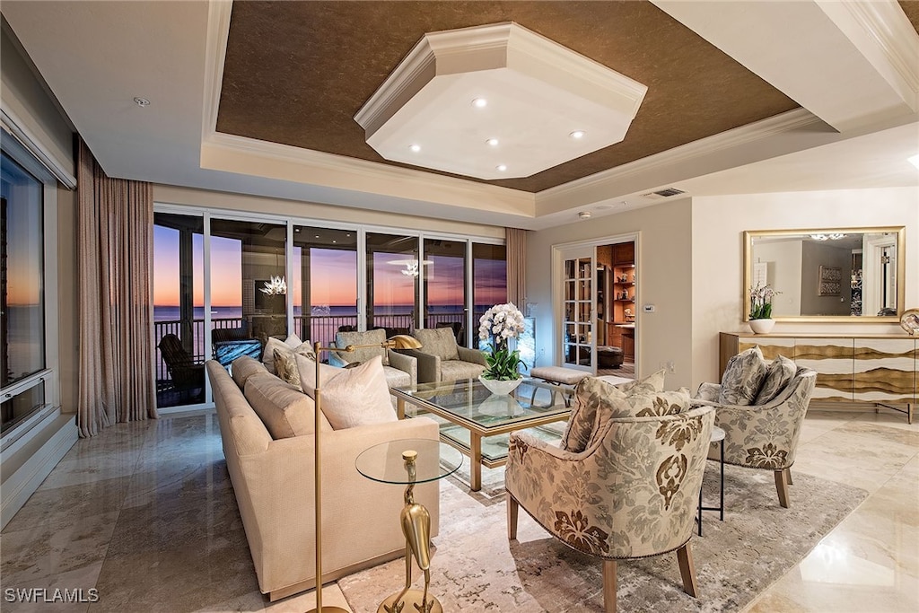 living room with a raised ceiling and crown molding