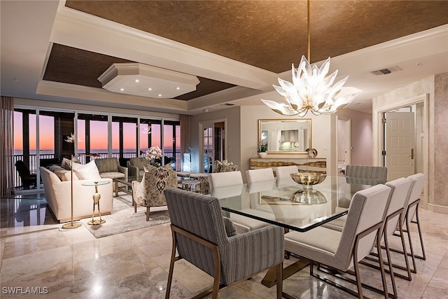 dining area with a raised ceiling, a notable chandelier, and crown molding