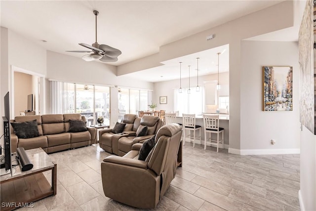 living room with baseboards and a ceiling fan