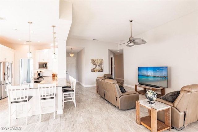 living area with a ceiling fan and baseboards