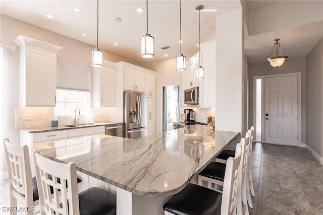 kitchen featuring a kitchen bar, pendant lighting, stainless steel appliances, and a sink