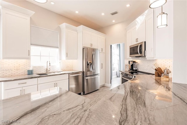 kitchen with appliances with stainless steel finishes, white cabinetry, decorative light fixtures, and light stone countertops