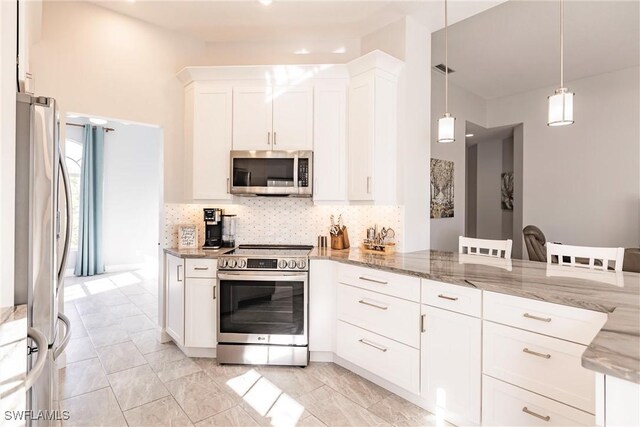 kitchen featuring tasteful backsplash, hanging light fixtures, appliances with stainless steel finishes, white cabinetry, and light stone countertops