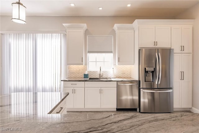 kitchen with a sink, stainless steel appliances, white cabinetry, pendant lighting, and backsplash