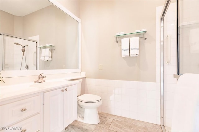 bathroom featuring toilet, a tile shower, tile walls, and vanity