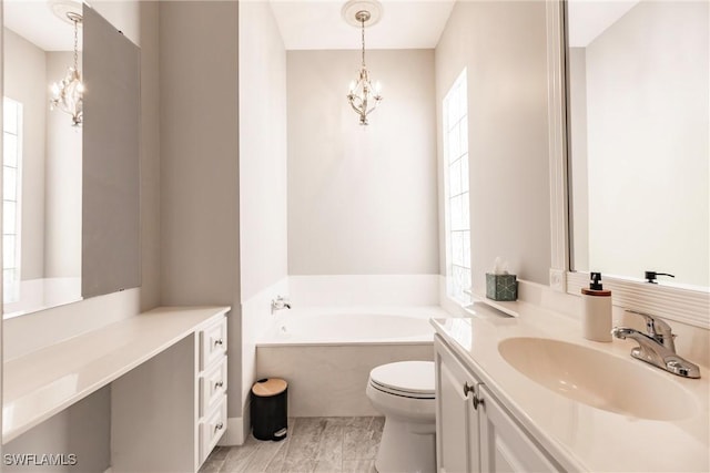 bathroom with a garden tub, a notable chandelier, vanity, and toilet