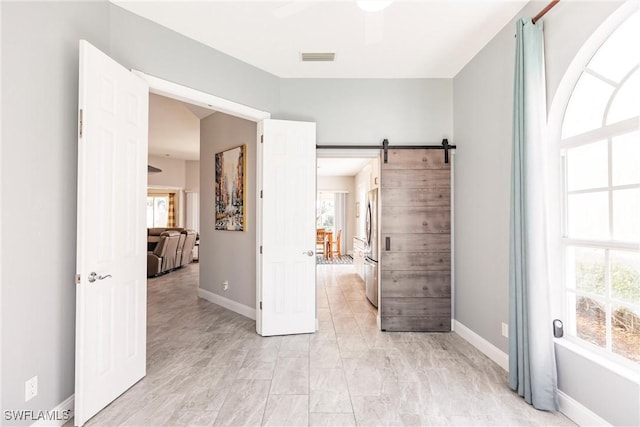 empty room featuring a healthy amount of sunlight, baseboards, and a barn door