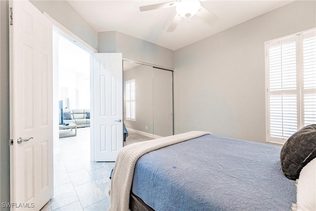 bedroom with light tile patterned floors, ceiling fan, and a closet