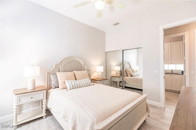 bedroom featuring light wood finished floors, a closet, visible vents, a sink, and baseboards