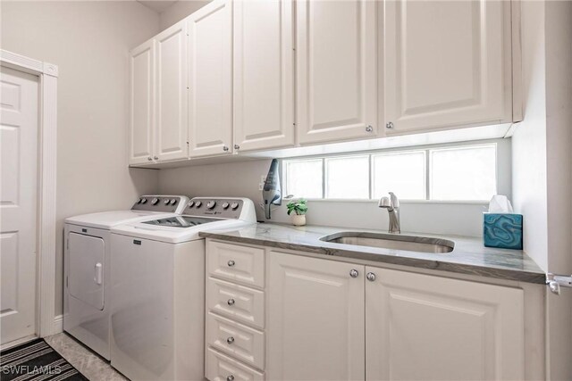 washroom featuring washing machine and dryer, cabinet space, and a sink