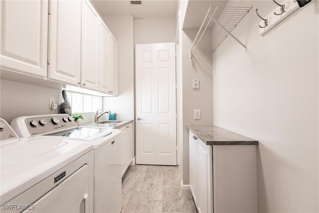 washroom featuring a sink, visible vents, washing machine and dryer, and cabinet space