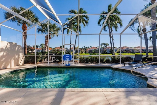 pool with a residential view, a patio area, and glass enclosure