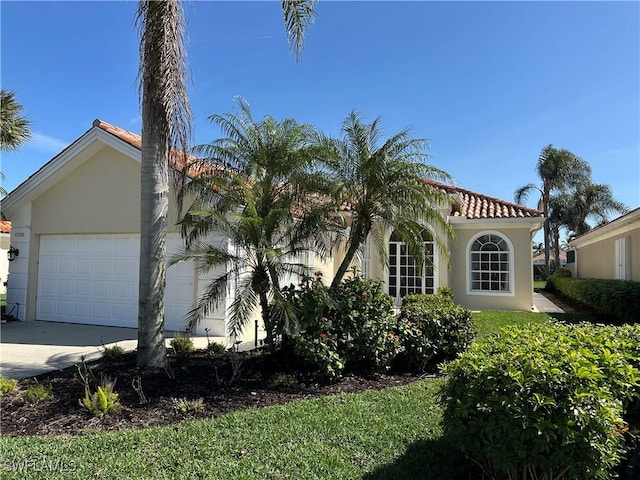 view of home's exterior with an attached garage, a tile roof, concrete driveway, and stucco siding