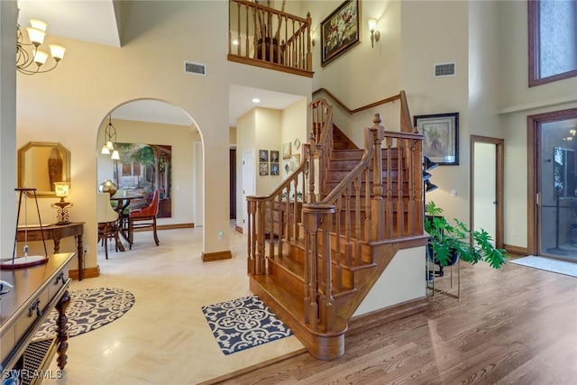 stairway with a high ceiling, a chandelier, and hardwood / wood-style flooring