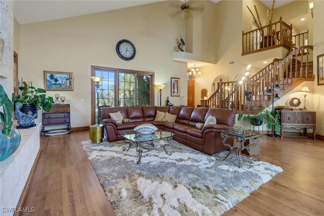 living room featuring ceiling fan with notable chandelier, a high ceiling, and hardwood / wood-style flooring