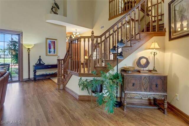 staircase featuring a high ceiling, a notable chandelier, and hardwood / wood-style floors