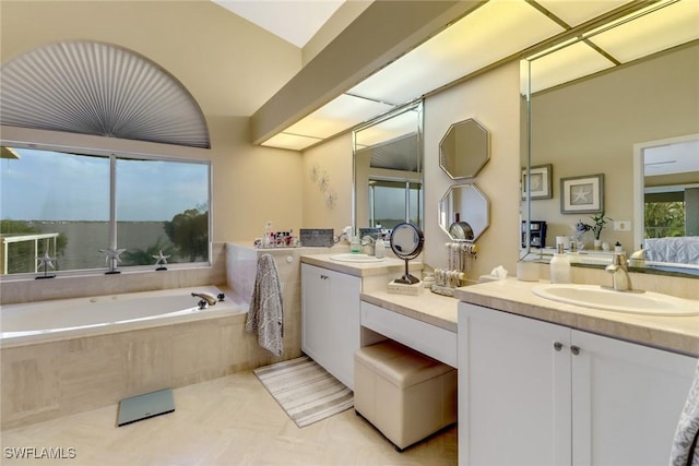 bathroom featuring tile patterned flooring, a relaxing tiled tub, and vanity