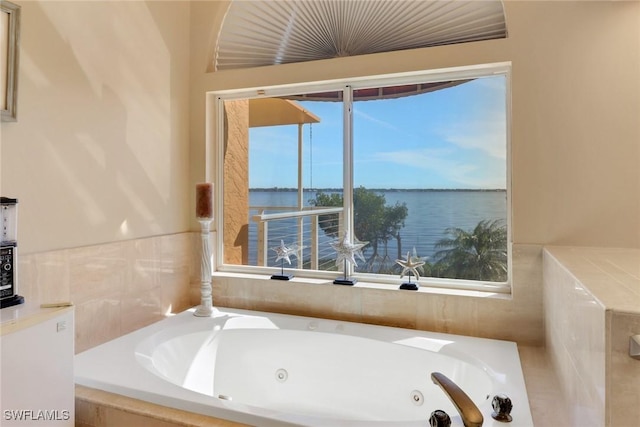 bathroom featuring tiled bath, a wealth of natural light, and a water view