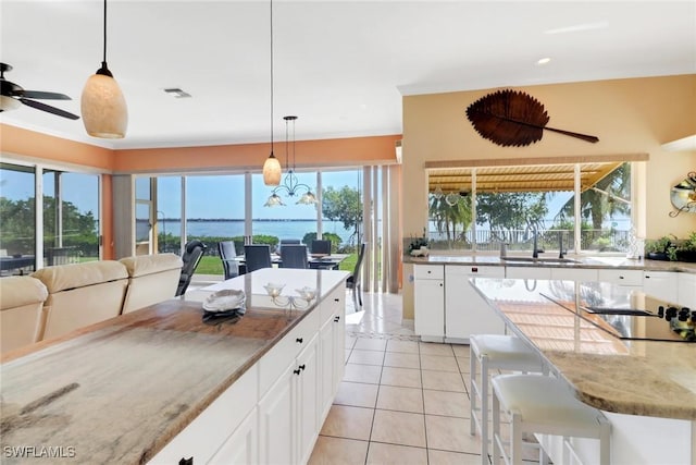 kitchen featuring decorative light fixtures, sink, light tile patterned floors, and white cabinetry