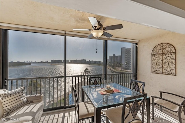 sunroom / solarium with a water view, ceiling fan, and a healthy amount of sunlight