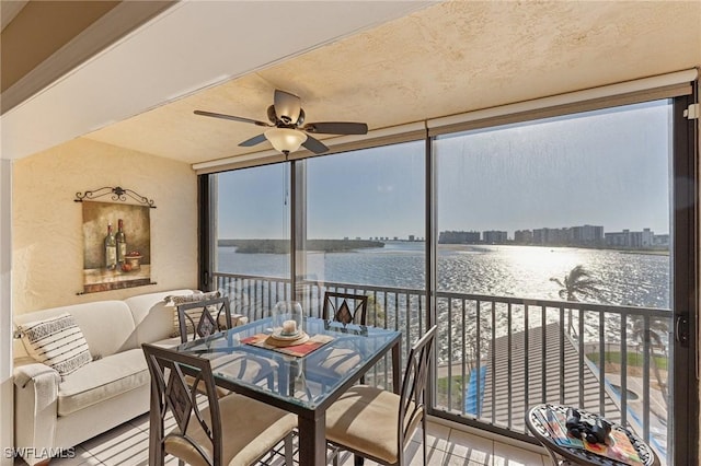 sunroom / solarium featuring a water view and ceiling fan