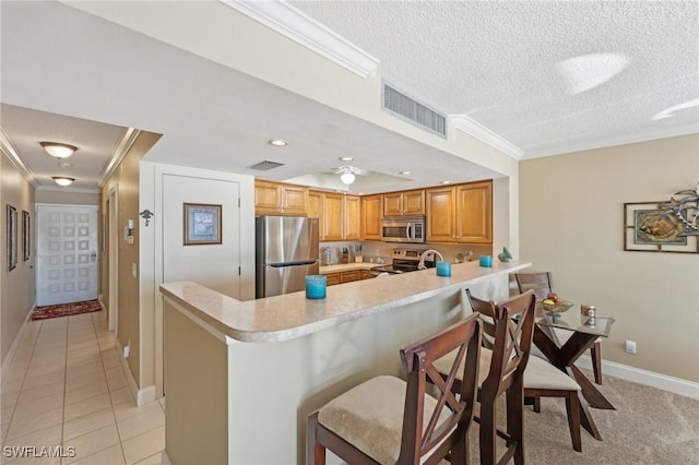 kitchen featuring a breakfast bar, kitchen peninsula, a textured ceiling, and appliances with stainless steel finishes