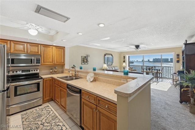 kitchen featuring kitchen peninsula, appliances with stainless steel finishes, light carpet, a textured ceiling, and sink