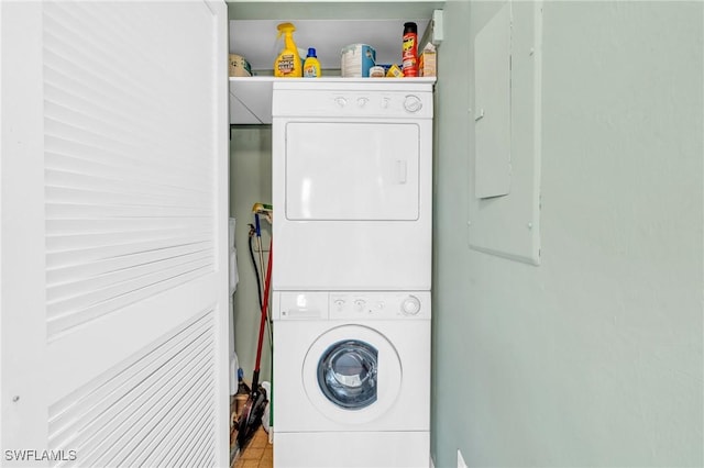 laundry room with electric panel and stacked washing maching and dryer