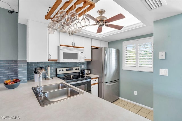 kitchen featuring appliances with stainless steel finishes, backsplash, sink, white cabinets, and light tile patterned flooring