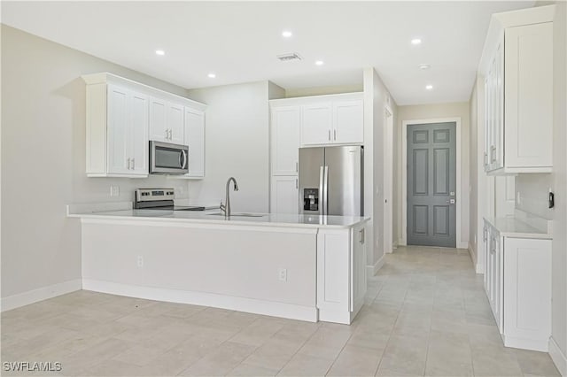 kitchen with white cabinetry, sink, kitchen peninsula, light tile patterned flooring, and appliances with stainless steel finishes