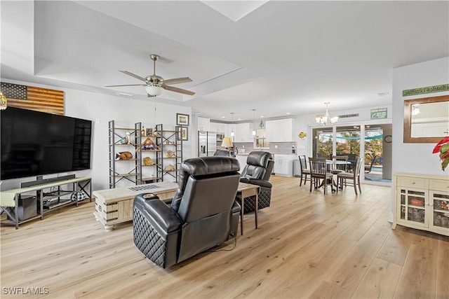 living room with light hardwood / wood-style flooring and ceiling fan with notable chandelier