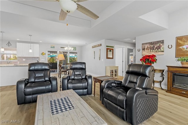 living room with sink, light hardwood / wood-style floors, and ceiling fan with notable chandelier