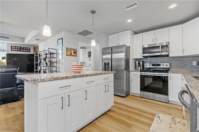 kitchen with white cabinets, pendant lighting, and stainless steel appliances