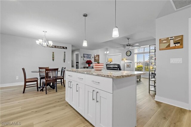 kitchen featuring a center island, ceiling fan with notable chandelier, light hardwood / wood-style flooring, decorative light fixtures, and white cabinetry