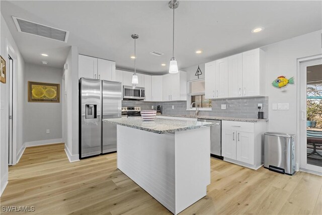 kitchen with a center island, white cabinets, stainless steel appliances, and light hardwood / wood-style flooring