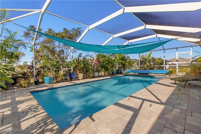 view of swimming pool featuring glass enclosure and a patio area