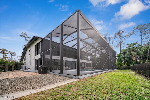 rear view of house featuring a yard, glass enclosure, and a patio area