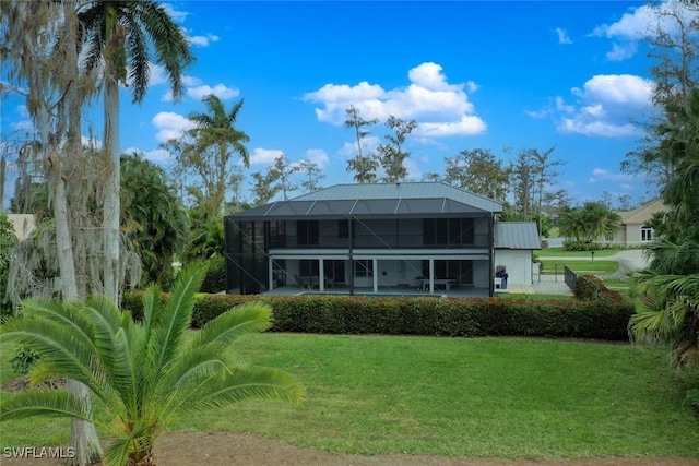 rear view of house with a yard and glass enclosure