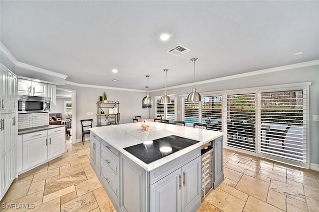 kitchen with pendant lighting, white cabinets, crown molding, black electric cooktop, and a kitchen island