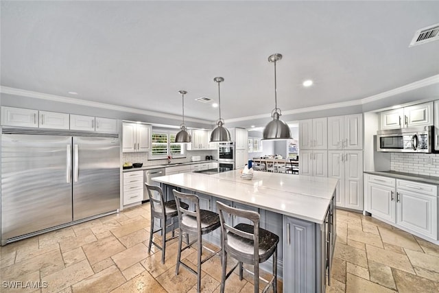 kitchen with stainless steel appliances, a spacious island, decorative light fixtures, a breakfast bar area, and white cabinets