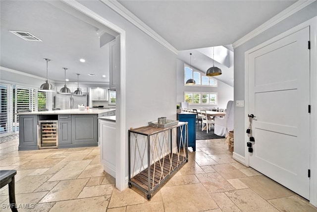 bar with pendant lighting, gray cabinets, ornamental molding, and beverage cooler